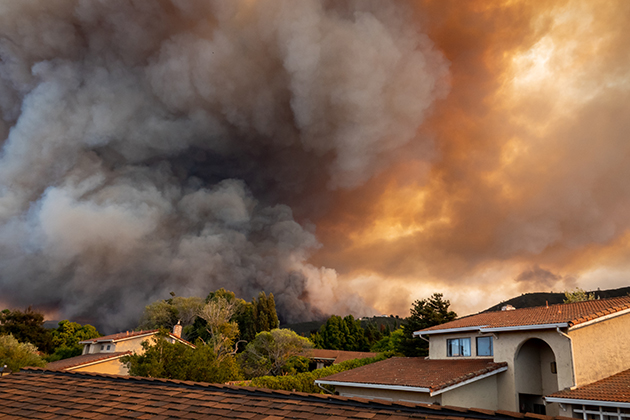 smoke from a wildfire encroaches on a community of residential houses