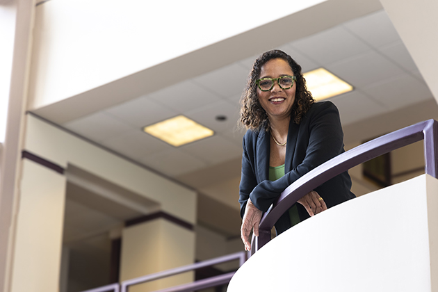 woman leaning on a staircase railing in an academic building