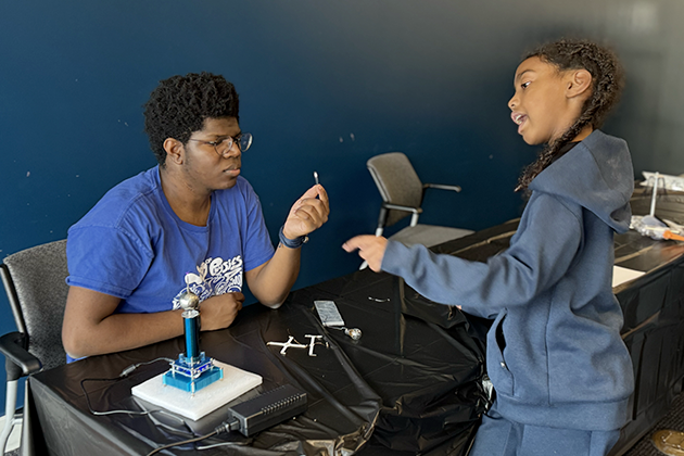 An elementary school students talks to a college graduate student.