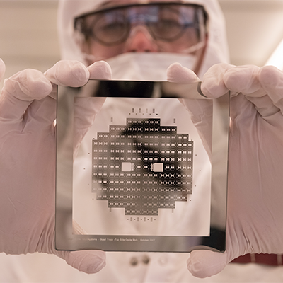A researcher holding a chip while in the Georgia Tech cleanroom, one of the largest of its kind in the U.S.