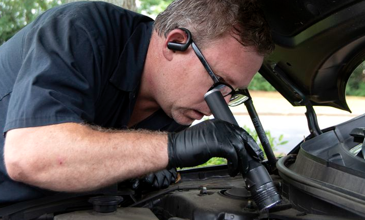 mechanic looking into car engine 
