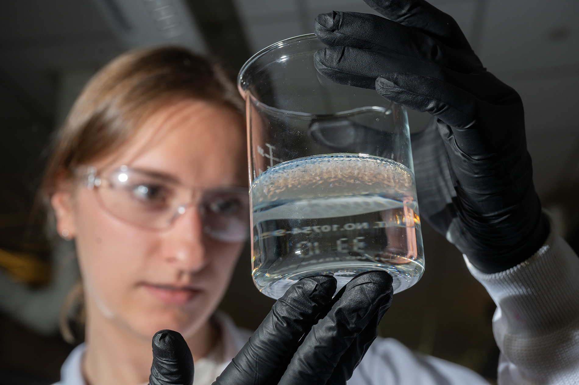 Female researcher at Georgia Tech looking at a beaker full of water and salt beads