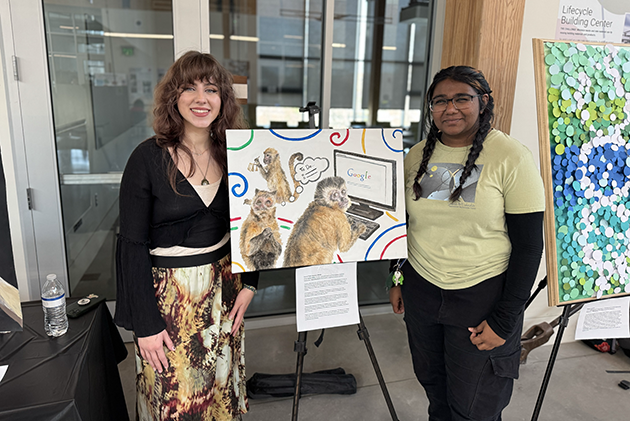 two women stand on either side of an art easel
