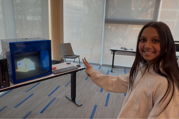 female student looking at herself as a hologram on a specialized piece of equipment