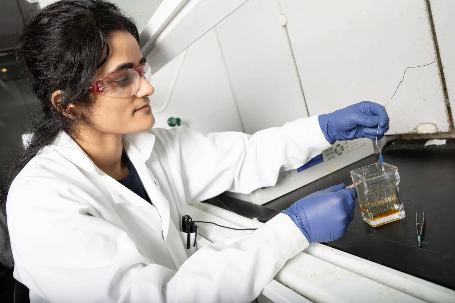 Postdoctoral scholar Anuja Tripathi examines a small sample of stainless steel after an electrochemical etching process she designed to create nano-scale needle-like structures on its surface. A second process deposits copper ions on the surface to create a dual antibacterial material.