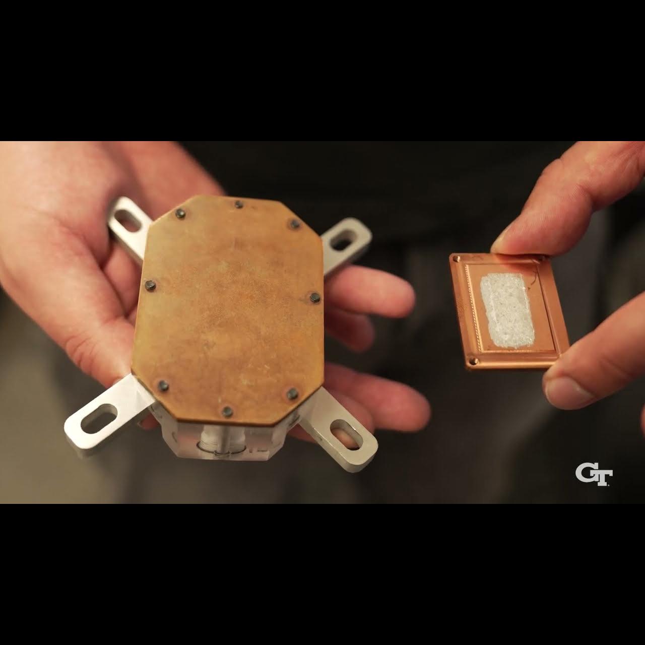 Two hands hold an electronic device that has the EMCOOL integrated liquid cooling technology as part of its enclosure.