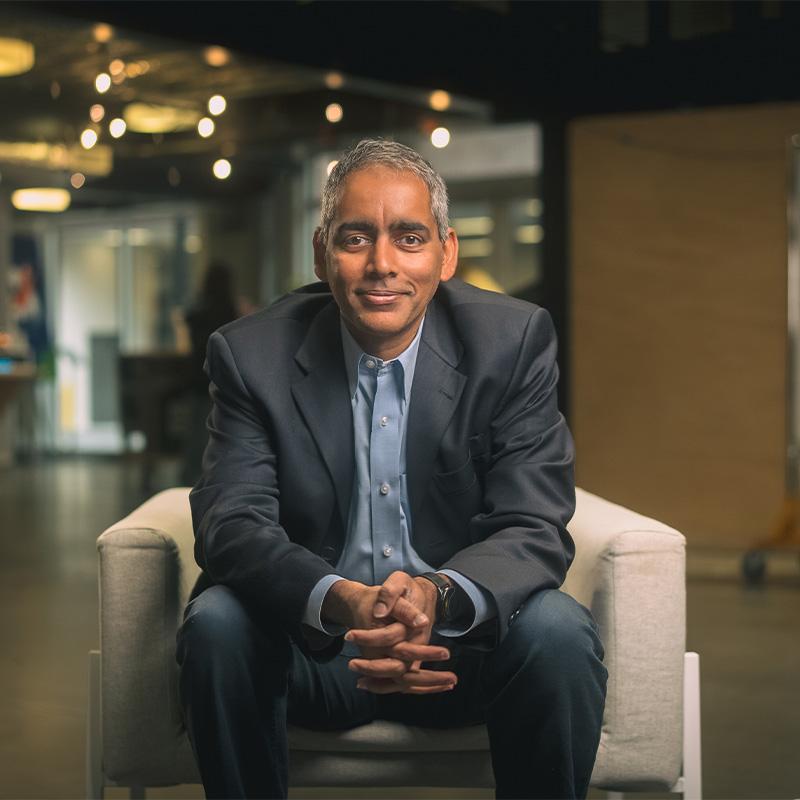 Professor Karthik Ramachandran sits in a chair with his hands clasped