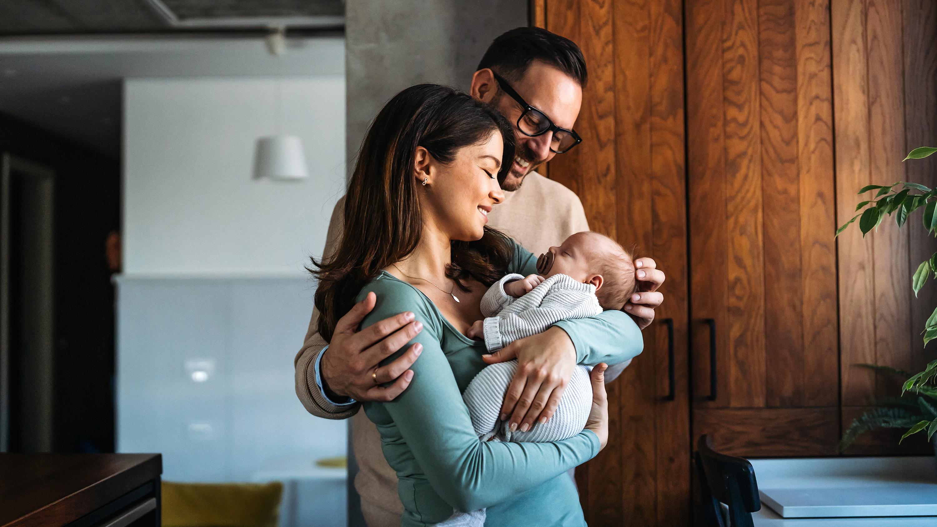 A young mother and father look at their baby.