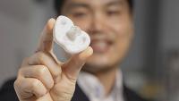 Hong Yeo holding a white pacifier under development at Georgia Tech