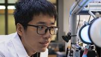 researcher with a white coat looking into a microscope