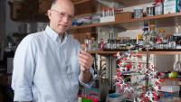 <p>Professor Nicholas Hud holds a vial containing synthesized molecules that spontaneously assemble into structures that resemble the helical structure of DNA (model in foreground).</p>