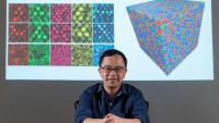 <p>Ting Zhu, professor of mechanical engineering at Georgia Tech, in front of his TEM images of polycrystalline metals and a graphic simulating atomic structure</p>