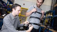 Researcher Aaron Young makes adjustments to an experimental exoskeleton worn by then-Ph.D. student Dean Molinaro.