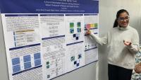Young woman standing in front of a poster describing her Parkinson's Disease research