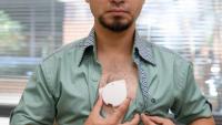 man baring chest an holding a patch against his skin