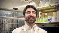 Headshot of Christos Athanasiou in his lab, wearing a white collared shirt and white lab coat