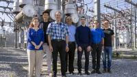 The TESLA (Tough and Ecological Supercritical Line Breaker for AC) team in front of high-voltage circuit breakers. 