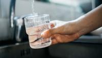 Hand holds glass over faucet