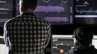 Two cybersecurity specialists monitor network activity.