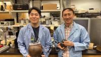 Two people in blue lab coats holding onggi - traditional Korean earthenware pots. 
