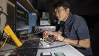 <p>GTRI researcher Paul Jo checks an RF test board with FCBGA packaged single-channel T/R module chips. (Credit: Sean McNeil, GTRI)</p>
