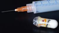 Prototype of an "exploding" capsule next to a syringe. The capsule can deliver medications that are typically only effective if injected.