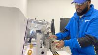 This is a photo of a technician at PBS Aeros space placing a part on a balancing machine in the company's manufacturing facility