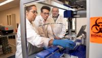 Emory researchers Lorena Chaves, Jose Assumpcao, and Philip Santangelo working at a hood in their lab. (Photo: Jack Kearse)
