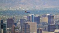 A view of Phoenix, Arizona with downtown, South Mountain, and a Southwest Airlines jet in frame.