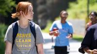 Photo Credit Ben Gray, AJC. A student wearing a "Serve-Learn-Sustain" tee shirt walks along a campus walkway with a Georgia Tech faculty member.