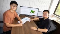 Ph.D student Simin Ma sits with Assistant Professor Shihao Yang at his desk. A computer monitor shows flu data and Google search trends that they used in their Covid and flu forecasting models.