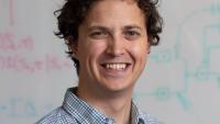 Simon Sponberg smiling in front of a whiteboard.