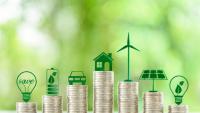 Stacks of coins topped with green icons representing clean energy and sustainability.