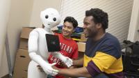 Two students interact with humanoid robot. 