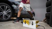 A gold and white charger box in front of a car