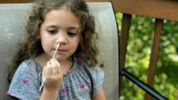 <p>A child swabs their nose for Covid-19 testing.</p>