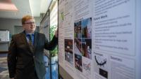 <p>GTRI Research Engineer Konrad Ahlin explains a poster on his "Hyper Redundant Flexible Manipulator (HRFM)" at the recent DARPA Forward conference held at Georgia Tech. (Credit: Sean McNeil, GTRI)</p>