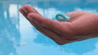 a person's hand, holding a small soft robot