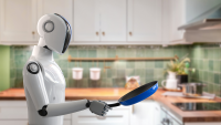 A white humanoid robot holds a blue pan while standing in a kitchen with a green backsplash