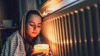 A young girl wrapped in a blanket holds a candle during a power outage.