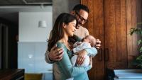 A young mother and father look at their baby.